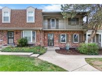 Charming brick townhouse featuring a balcony, dormer windows, and well-maintained landscaping at 7355 S Knolls Way, Centennial, CO 80122