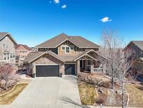 Charming two-story home with stone accents, a covered porch, a well-manicured yard, and a two-car garage at 7680 S Blackstone Pkwy, Aurora, CO 80016