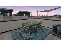 Rooftop deck features an outdoor dining set, shade, and city views at 1836 Grove St # 108, Denver, CO 80204