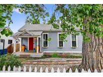 Charming home featuring a welcoming red door, a covered front porch, and a well-maintained lawn at 1448 Depew St, Lakewood, CO 80214