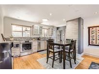 Bright kitchen features stainless appliances, wood floors and breakfast nook with seating at 3020 Niagara St, Denver, CO 80207