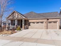 Charming brick home with a covered front porch and a spacious two-car garage on a sunny day at 22647 Hopewell Ave, Parker, CO 80138