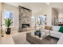 Bright living room with fireplace, light wood floors and large windows at 1764 Peak Loop, Broomfield, CO 80023