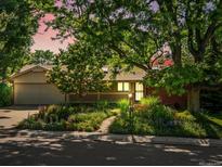 Charming ranch home featuring mature trees, beautiful landscaping, and a welcoming covered porch at 1985 Union St, Lakewood, CO 80215