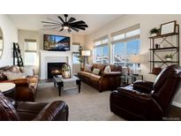 Bright living room with fireplace, large windows and leather sofas at 6612 Merrimack Dr, Castle Pines, CO 80108