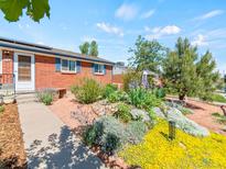 Brick home featuring a beautifully landscaped front yard with colorful flowers and mature trees at 4163 S Decatur St, Englewood, CO 80110