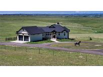 Charming home with an attached garage, beautiful landscaping, circular driveway, and picturesque mountain views at 7600 Patrick Trl, Elizabeth, CO 80107