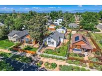 Charming home featuring a manicured lawn, complemented by mature trees and vibrant landscaping under a clear, sunny sky at 4883 Perry St, Denver, CO 80212