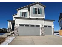 Two-story home with gray siding, two-car garage, and landscaping at 17751 E 93Rd Ave, Commerce City, CO 80022