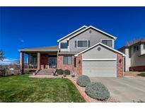 Charming two-story home featuring a brick and gray exterior, with a covered porch and well-manicured lawn at 6271 Mcintyre Way, Golden, CO 80403