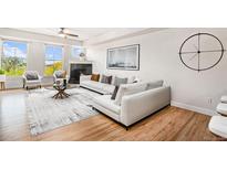 Bright living room with hardwood floors, large windows, fireplace, and a comfortable white sofa at 1699 N Downing St # 302, Denver, CO 80218