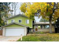 Charming two-story home with a brick and siding exterior, a large front yard, and mature trees at 11237 W 59Th Ave, Arvada, CO 80004