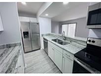 A bright kitchen features stainless steel appliances, white cabinets, and granite countertops at 12223 E Ford E Ave # 12223, Aurora, CO 80012