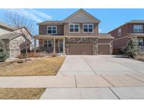 Charming two-story home featuring a stone and tan siding exterior with a three car garage and well-maintained lawn at 6472 N Dunkirk Ct, Aurora, CO 80019