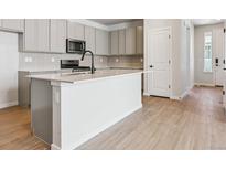 Bright kitchen features gray cabinets, stainless steel appliances, island and wood flooring at 14123 Deertrack Ln, Parker, CO 80134