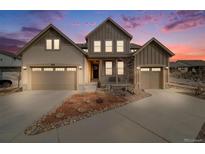 Two story home boasting a three car garage, tidy front yard, and pleasant curb appeal with colorful sunrise in background at 9742 Taylor River Cir, Littleton, CO 80125