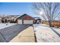 Brick home with three-car garage and snowy front yard at 10976 W 55Th Ln, Arvada, CO 80002