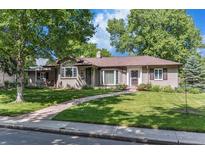 Charming single-story brick home with lush green lawn, mature trees, and inviting walkway at 801 S Steele St, Denver, CO 80209