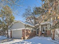 Two-story house with gray siding, brick accents, and a two-car garage; winter scene at 2676 S Troy Ct, Aurora, CO 80014