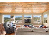 Inviting living room featuring mountain views from oversized windows and wood plank ceiling at 27341 Ridge Trl, Conifer, CO 80433