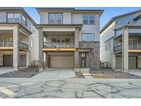 Modern two-story townhome with a gray exterior, a balcony, a two-car garage, and brick accents at 3172 S Russell St, Morrison, CO 80465
