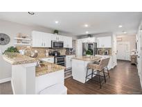 Bright kitchen boasts granite counters, stainless steel appliances, and a charming breakfast bar with seating at 13340 Saint Paul St, Thornton, CO 80241