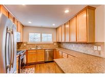 Well-lit kitchen with stainless steel appliances, granite countertops, and updated tile backsplash and flooring at 546 Lost Valley Pt, Castle Rock, CO 80108