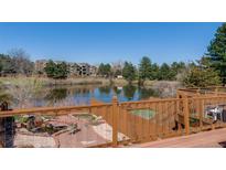 A beautiful pond-side view showcases mature trees and landscaping from the outdoor deck at 163 Ward Ct, Lakewood, CO 80228