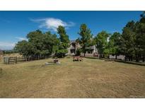 Home with lush green lawn and mature trees under a blue sky at 8853 N Awl Rd, Parker, CO 80138