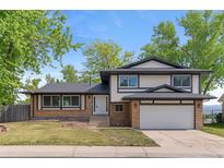 Charming two-story home featuring brick and siding, a well-manicured lawn, and an attached two-car garage at 12992 W Jewell Cir, Lakewood, CO 80228