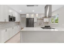 Stylish kitchen featuring white cabinets, stainless steel appliances, and a contemporary backsplash at 12992 W Jewell Cir, Lakewood, CO 80228