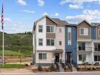Inviting exterior of a multi-level townhouse with white and brown siding plus landscaped front at 14492 Pansy Loop, Morrison, CO 80465