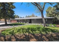 Charming single-story home boasts a well-maintained lawn and a brick exterior, complemented by mature trees at 8540 W 59Th Ave, Arvada, CO 80004