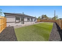 View of fenced backyard featuring artificial turf and rock landscaping with a modern styled home at 3216 Elizabeth, Denver, CO 80205