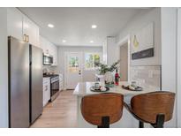 Beautiful updated kitchen features stainless steel appliances, white cabinets, and breakfast bar with seating at 3216 Elizabeth, Denver, CO 80205