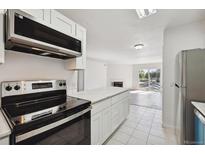 Bright kitchen boasts stainless appliances, white cabinetry, and a center island open to the living area at 13095 W Cedar Dr # 302, Lakewood, CO 80228