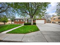 Charming brick home with a well-manicured lawn and mature trees providing shade and curb appeal at 12176 W Ohio Pl, Lakewood, CO 80228