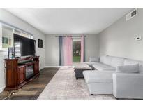 Bright living room with a gray sectional couch, fireplace, and sliding glass doors to the outside at 10211 Ura Ln # 8-102, Thornton, CO 80260
