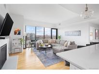Bright, open living room with modern decor, a fireplace, and a large window with city views at 2990 E 17Th Ave # 1004, Denver, CO 80206