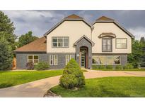 Charming two-story home boasts a unique facade, a manicured lawn, and beautiful landscaping at 22 Rangeview Dr, Wheat Ridge, CO 80215