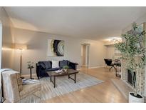 Inviting living room featuring a fireplace, wood floors, a blue sofa, and a dining space at 3550 S Harlan St # 259, Denver, CO 80235