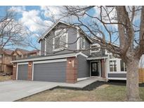 Charming two-story home with a three-car garage, gray siding, and red brick accents at 12690 Utica Cir, Broomfield, CO 80020