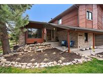 Charming brick and wood exterior with a well-manicured rock garden and inviting covered porch with blue seating at 8072 Windwood Way, Parker, CO 80134