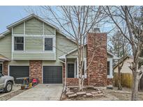Inviting two-story home with a well-maintained lawn, attached garage, and classic brick chimney at 1696 Geneva Cir, Longmont, CO 80503