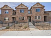 Charming townhome with brick facade, fenced front yard, and well-maintained landscaping at 6777 S Old Hammer Ct, Aurora, CO 80016