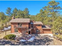 Charming multi-level home featuring a deck, landscaping, and an attached two car garage in a lush, wooded area at 29571 Dorothy Rd, Evergreen, CO 80439