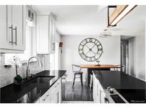 Bright kitchen features white cabinetry, stylish backsplash, and black countertops, creating a modern and inviting space at 11354 Allendale Dr, Arvada, CO 80004