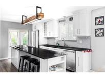 Modern white kitchen with stainless steel appliances, black countertops, and island with breakfast bar at 11354 Allendale Dr, Arvada, CO 80004