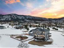 Beautiful exterior view of home with snow-covered yard, mountains in the background, and a play area for children at 931 Forest View Rd, Monument, CO 80132