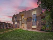 Exterior view of a charming brick apartment building with well-maintained landscaping and colorful sunset at 7755 E Quincy Ave # 301A7, Denver, CO 80237